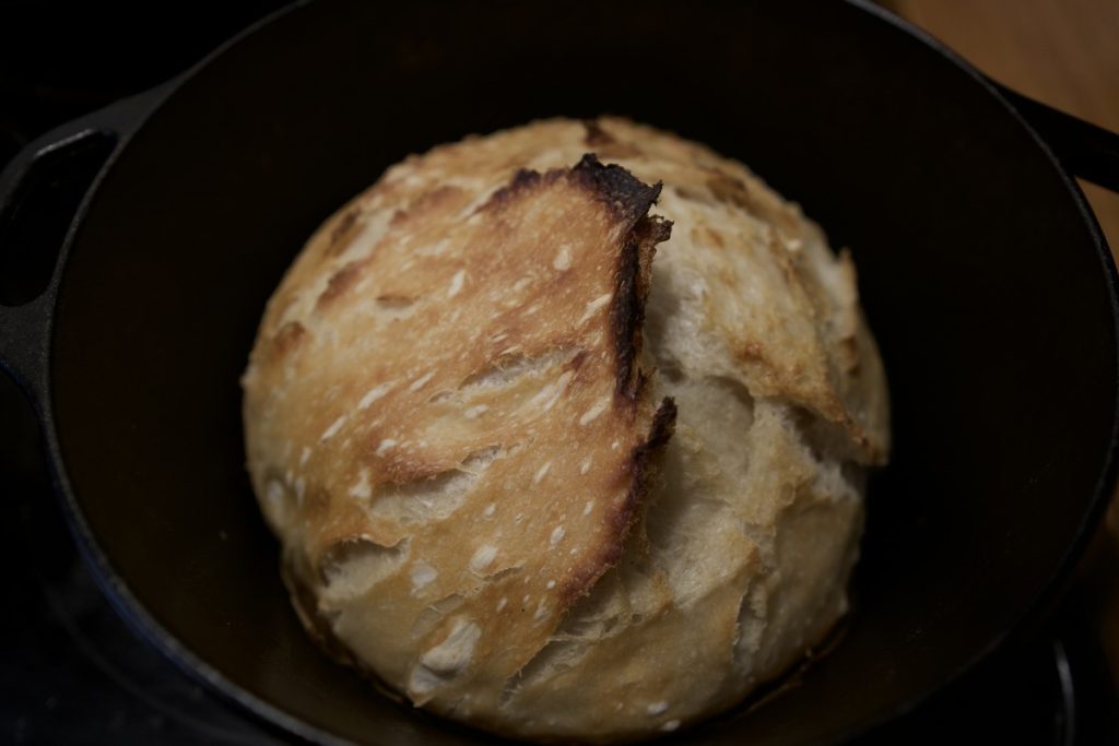 sourdough loaf just finished baking in cast iron dutch oven browned slightly on top