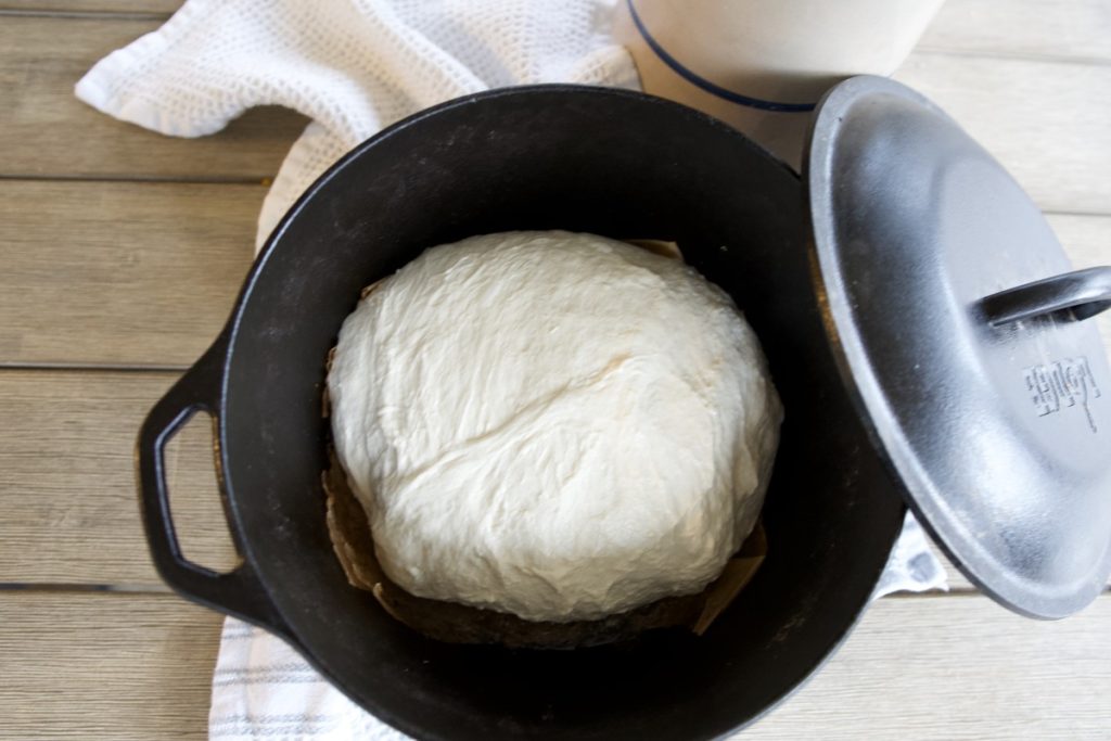 sourdough bread dough in cast iron dutch oven, folded and ready to bake in oven