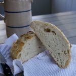 finished no knead sourdough bread, cut in half on tea towel
