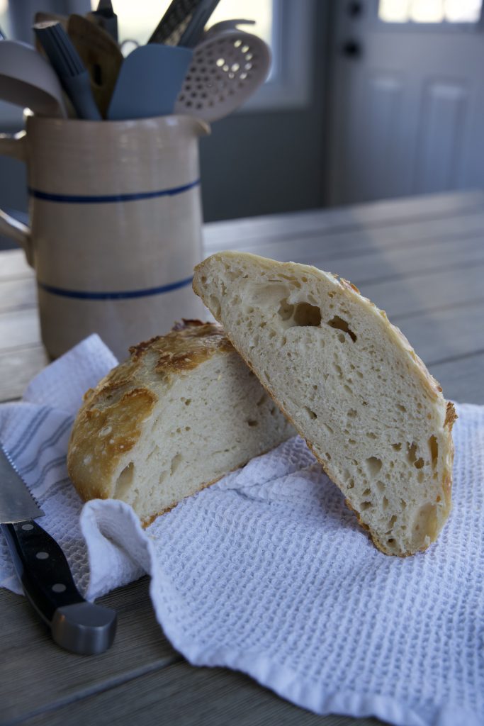 Baked no knead sourdough bread, cut in half on tea towel