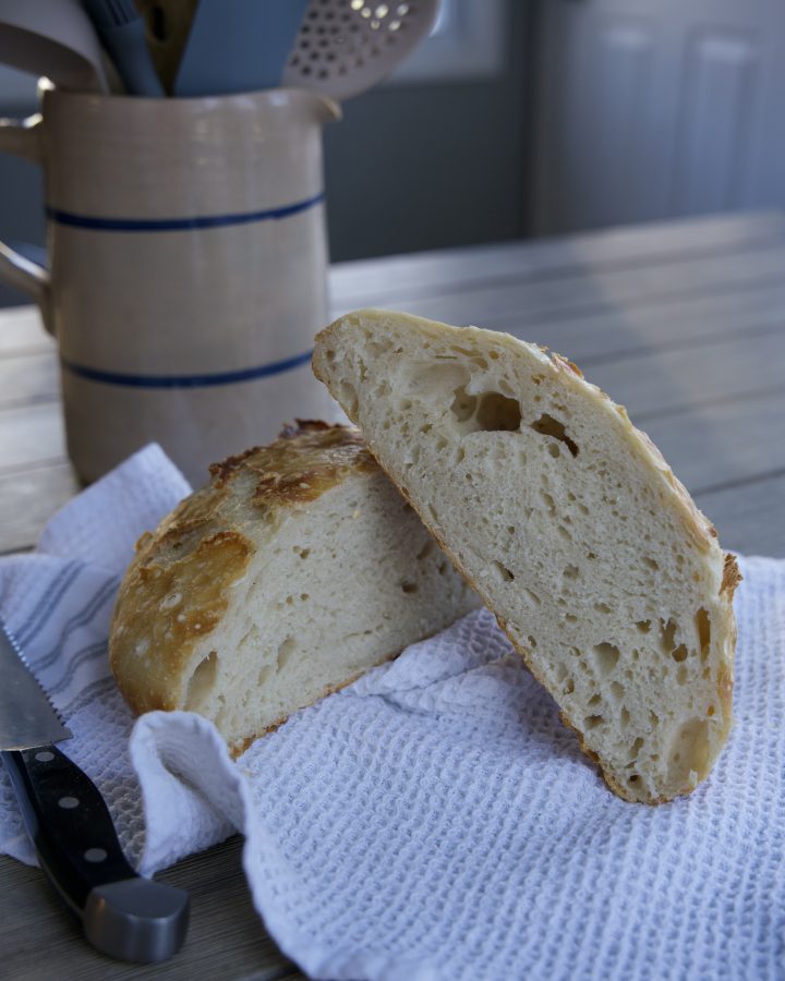 finished no knead sourdough bread, cut in half on tea towel