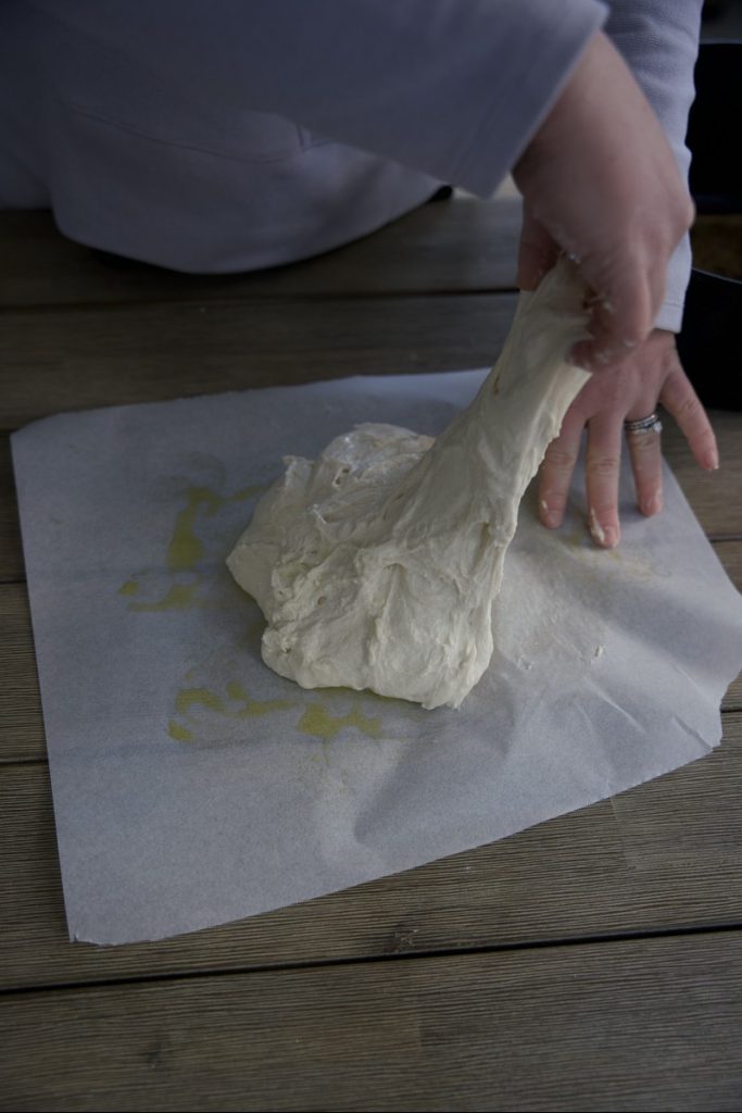 woman doing envelope stretch for sourdough envelope fold