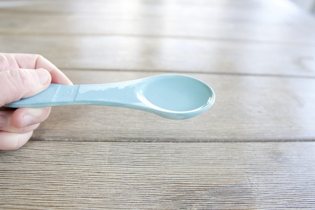 1 tablespoon of flour in blue tablespoon for simple from scratch sourdough starter recipe