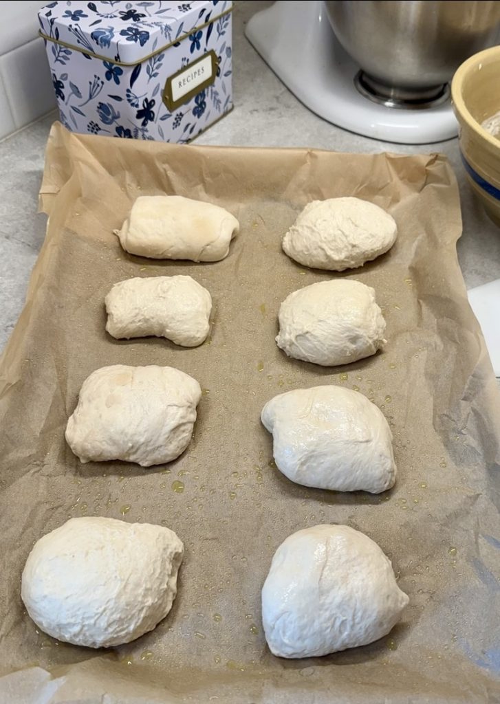 sourdough ciabatta bread dough rolls on greased parchment paper before rise.