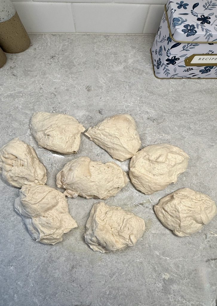 ciabatta bread dough cut into 8 portions on white countertop before envelope fold