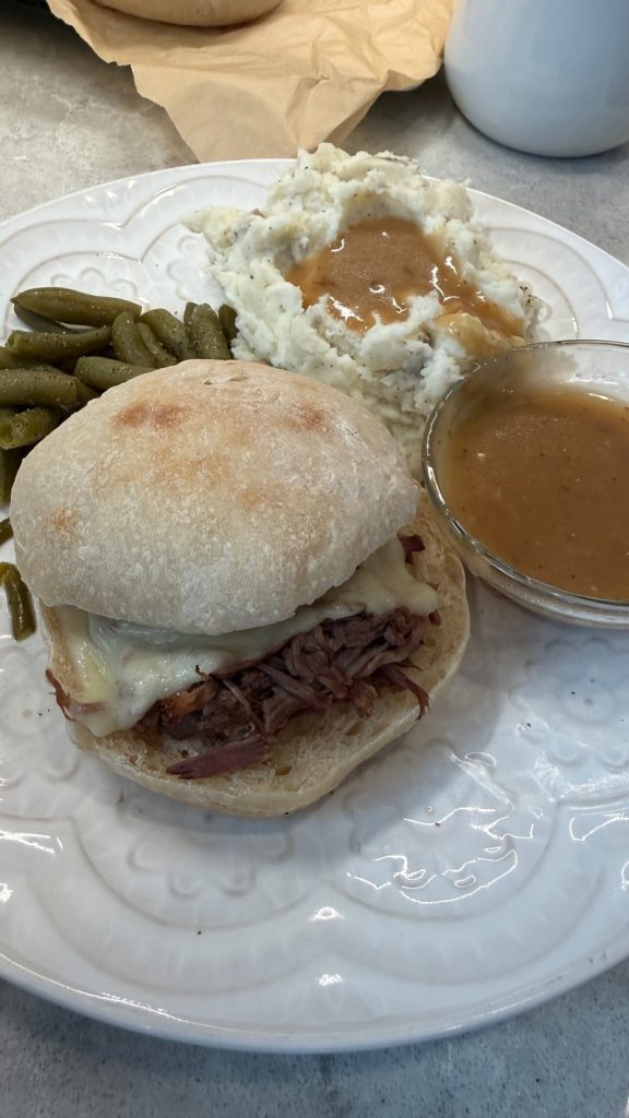 french dip sandwich on sourdough ciabatta bread roll with green beans, mashed potatoes and Au ju