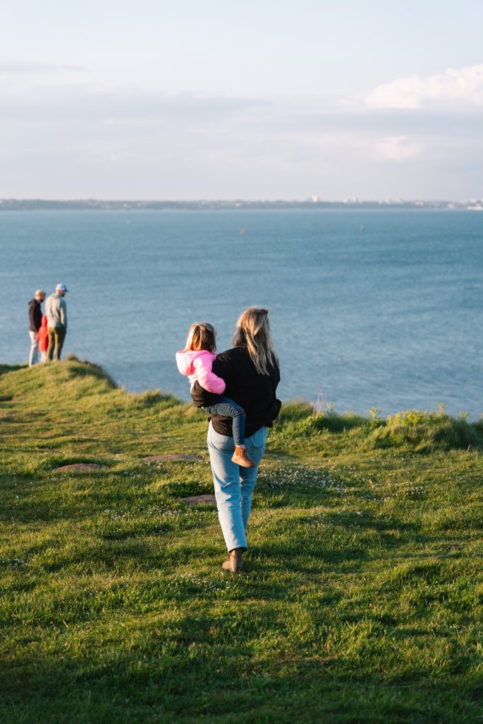 woman carrying child on sea cliffs in england