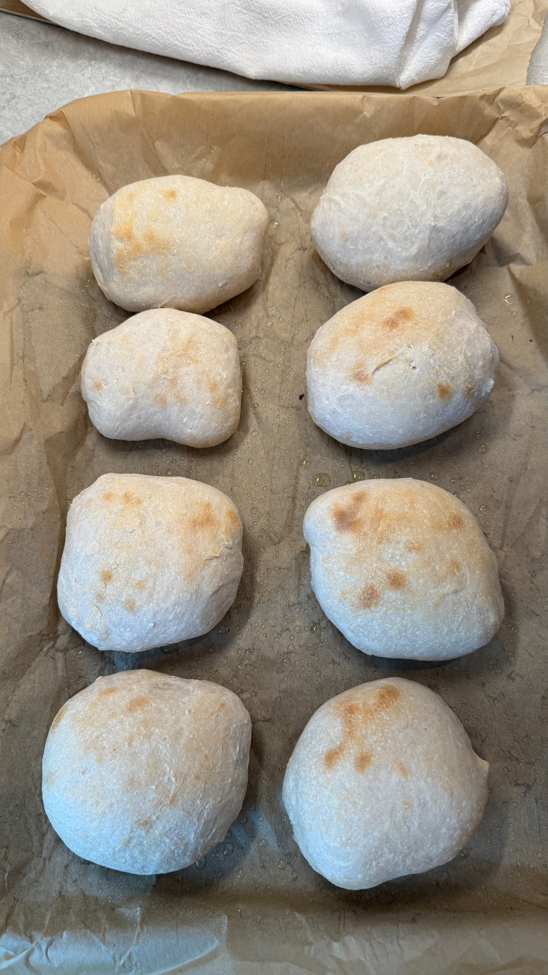 sourdough ciabatta bread rolls after baking on parchment paper lined baking sheet