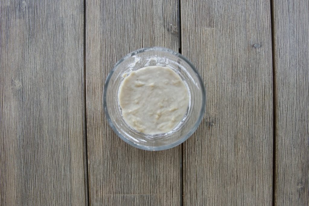 small glass bowl with water and flour mixture on day 2 from simple sourdough starter recipe before discard and feeding