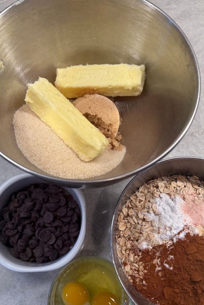 ingredients for oatmeal chocolate chip cookie dough in 4 different bowls on white counter top