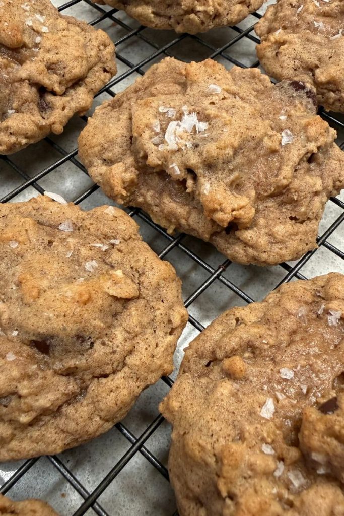 baked oatmeal chocolate chip cookies on cooling rack with finishing salt on top for the best oatmeal chocolate chip cookie recipe