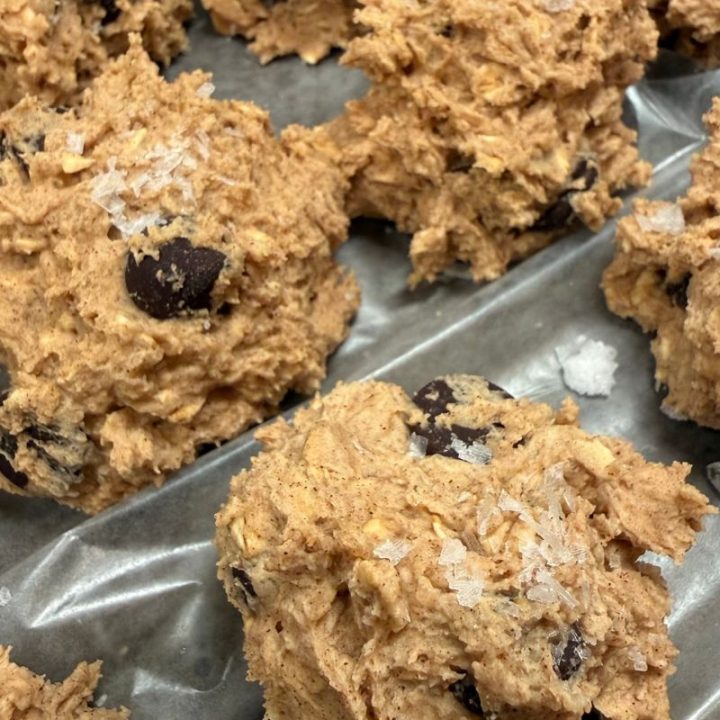 Oatmeal chocolate chip cookie dough rolled into balls on lined baking dish with wax paper